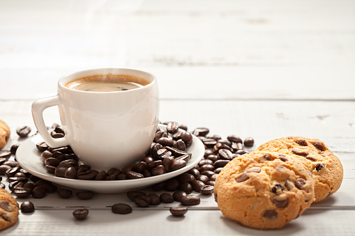 Small coffee cup with hot esspresso on old white table. This file is cleaned and retouched.