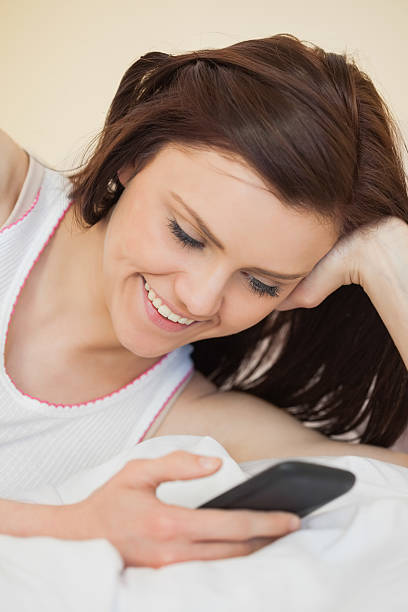 istock Cheerful girl using a mobile phone lying on a bed 502037183