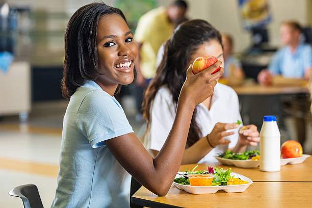 teen uczniem jedzenie zdrowy obiad w szkolnej stołówce - apple eating healthy eating friendship zdjęcia i obrazy z banku zdjęć