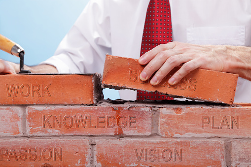 Businessman building a brick wall.  A conceptual image for building a solid business.