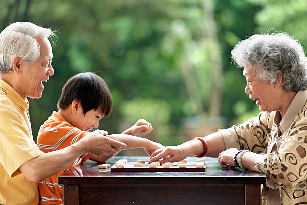 nonno, nonna e nipote giocare a scacchi xiangqi (cinese) - concentration chess playing playful foto e immagini stock
