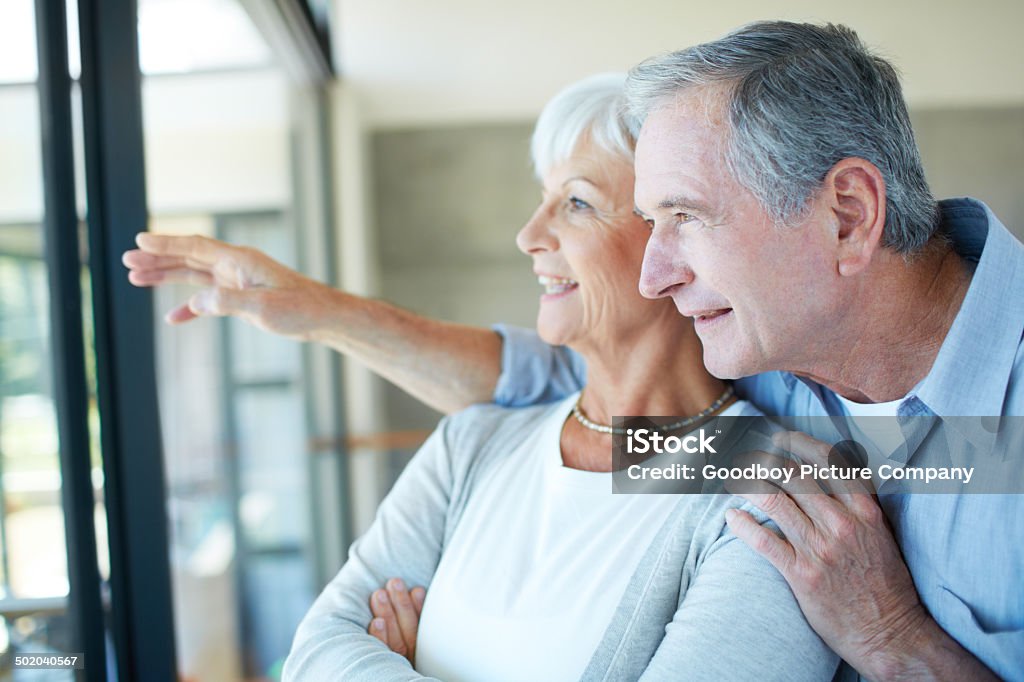 Planning the new garden Shot of a happy retired couple looking out a window in their home Headshot Stock Photo