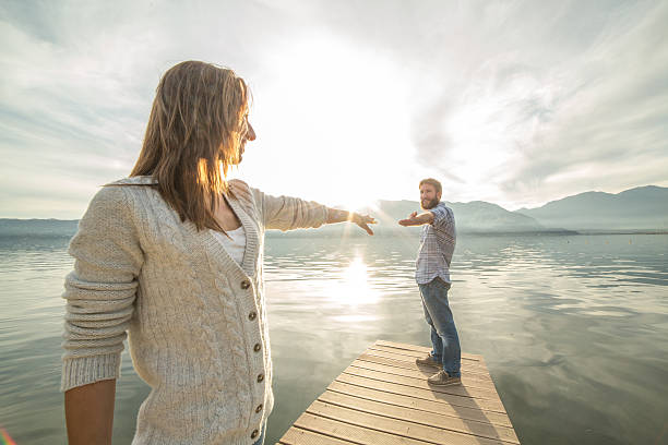 istock Couple on jetty, pulls out hands to reach each other 502041242