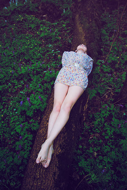 istock Young beautiful woman lying on log in forest 502041610