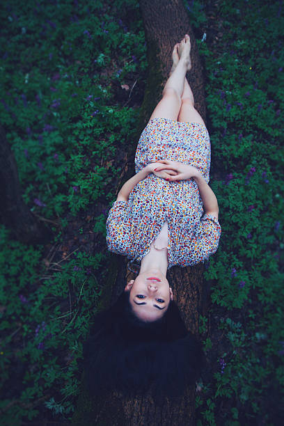 istock Young beautiful woman lying on log in forest 502041896