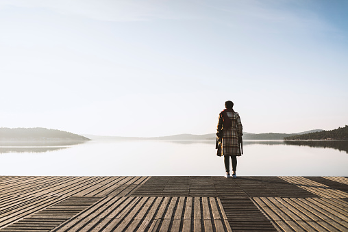 Woman standing on the jetty on a misty day, alone, looking away