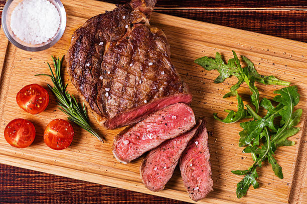 rib-eye-steak mit rucola-salat und tomaten. - butchers block stock-fotos und bilder