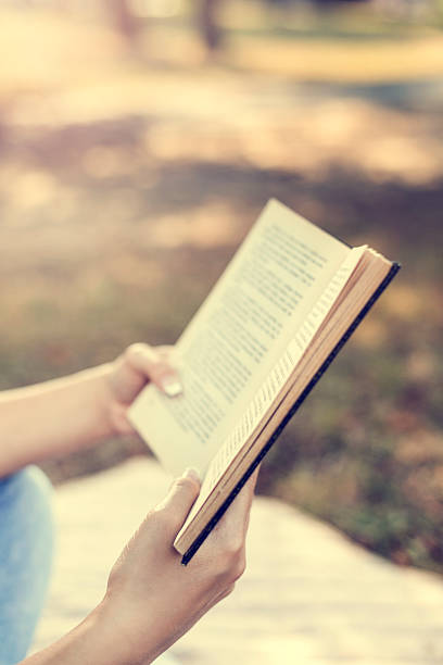 istock Young woman reading a book in the park 502046698