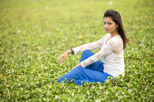 Pretty Indian young women relaxing on green lawn