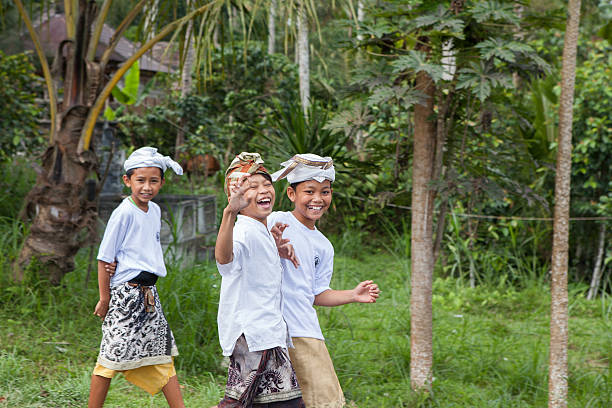 Bali, Indonesia - August 7, 2012: Children is walking on a street to a temple during a ceremony in the national dress.