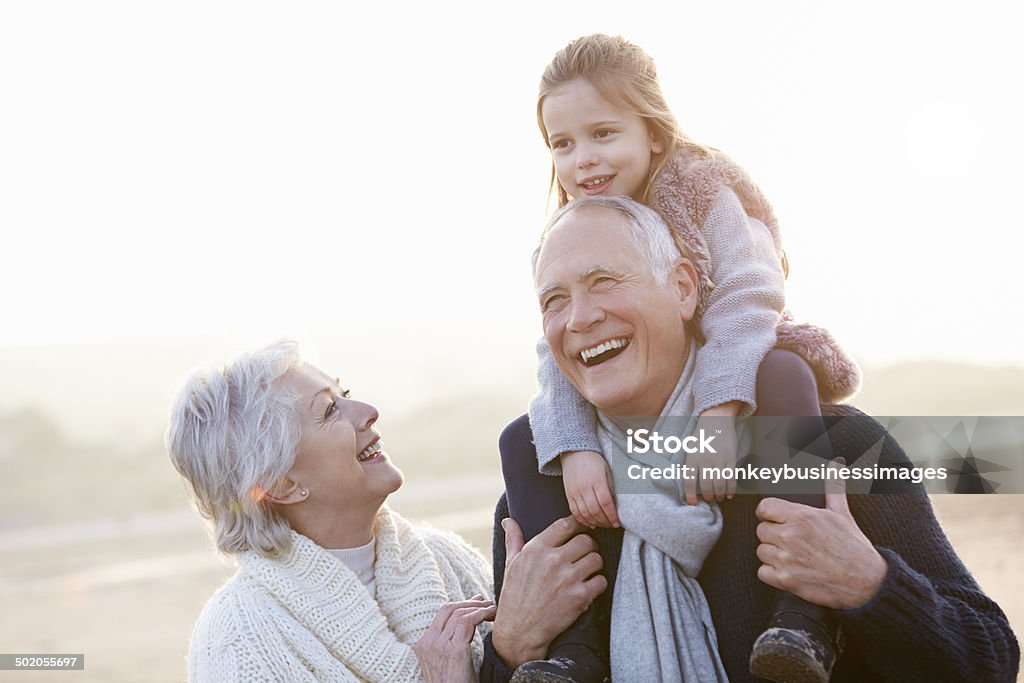 Großeltern mit Enkelin gehen auf Winter Beach - Lizenzfrei Großeltern Stock-Foto