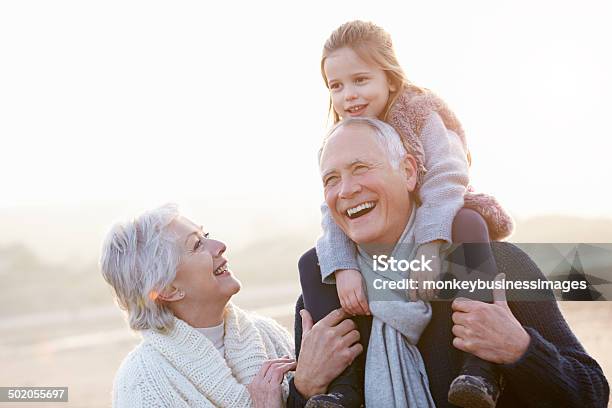 Abuelos Y Granddaughter A Pasos De La Playa De Invierno Foto de stock y más banco de imágenes de Abuelos