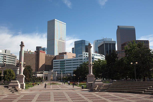 The downtown Denver, Colorado skyline with office buildings, hotels, and apartments rises behind the columns and steps in Civic Center Park. A Denver landmark, original construction of Civic Center Park was 1912 - 1920 and since, has been placed on the National Register of Historic Places.