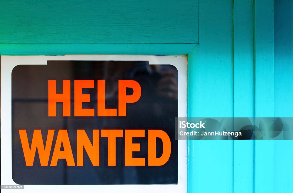 Help Wanted Sign in Old Blue Window An orange and black "Help Wanted" sign in an old blue window. Help Wanted Sign Stock Photo
