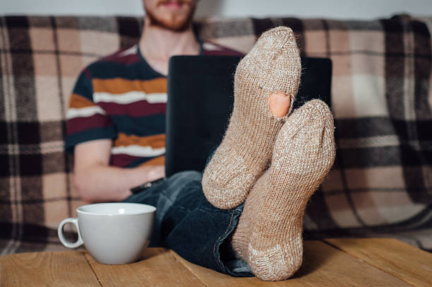 istock Young man working with laptop in holey socks 502075462
