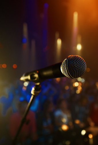 A microphone standing on a stage with a crowd in the background. This concert was created for the sole purpose of this photo shoot, featuring 300 models and 3 live bands. All people in this shoot are model released.