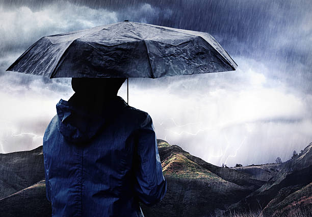 The perfect storm... Shot of a woman covered with an umbrella watching a thunderstorm over a mountainhttp://195.154.178.81/DATA/i_collage/pi/shoots/783670.jpg colour enhanced stock pictures, royalty-free photos & images