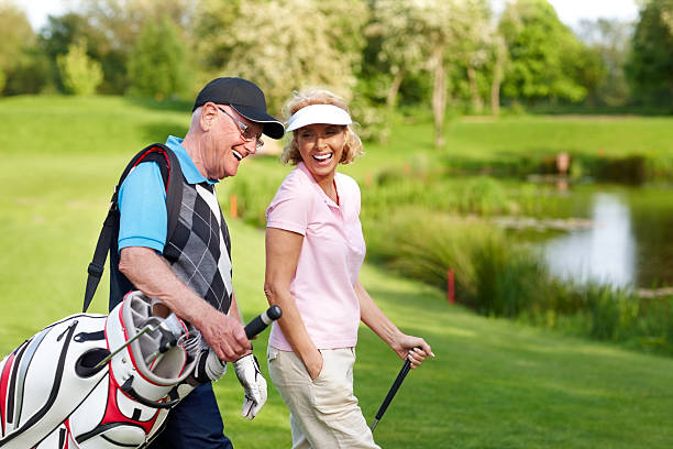 joyeux couple d'âge mûr marchant sur un parcours de golf - golf hobbies happiness cheerful photos et images de collection