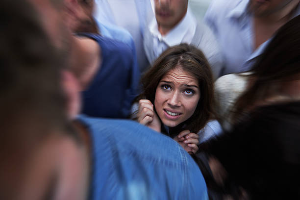 Drowning in people Shot of a fearful young woman feeling trapped by the crowd phobia stock pictures, royalty-free photos & images