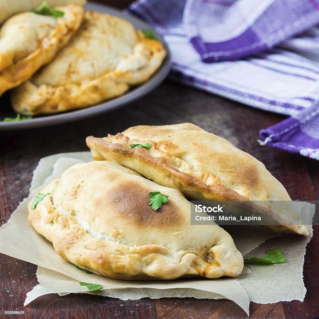 Mini calzone, closed pizza, Italian pastry stuffed with cheese Mini calzone, closed pizza, Italian pastry stuffed with cheese, meat, tomato sauce, tasty dish Cornish Pasty Stock Photo