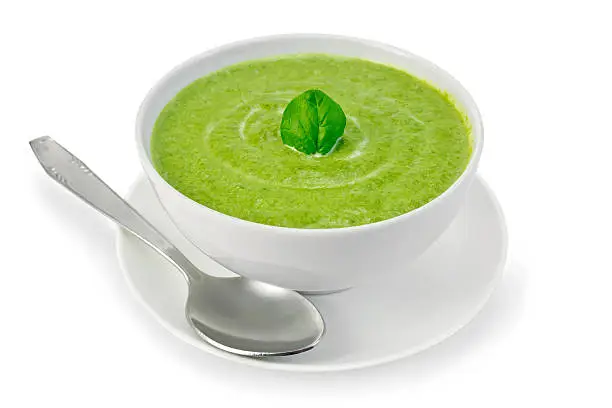 Cream soup green from spinach in a white bowl with leaf spinach on a plate isolated on white background