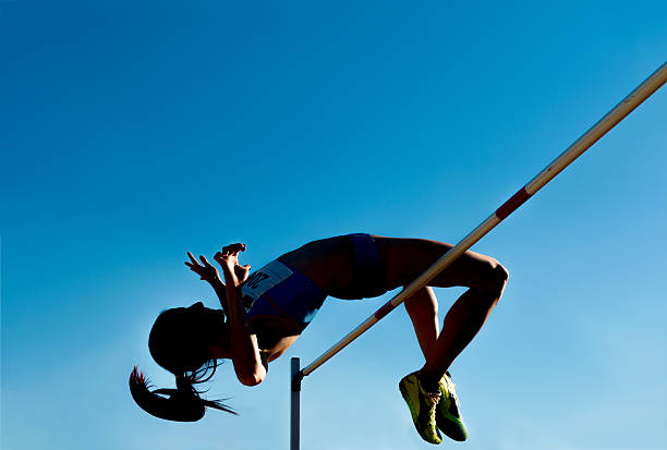 High jump silhouette against the blue sky Side view of young woman at high jump, silhouette high jump stock pictures, royalty-free photos & images