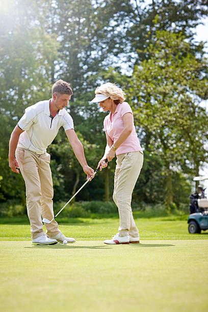istock Golf pro teaching female golfer on putting green 502090219