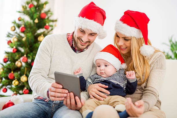 Happy young family celebrating Christmas Happy family in the room with the Christmas tree.The family is enjoying in the holidays.They are celebrating their first Christmas together. baby new years eve new years day new year stock pictures, royalty-free photos & images