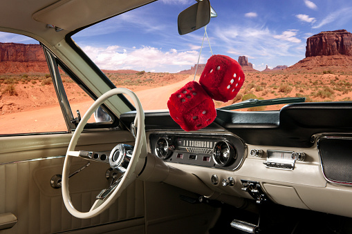 Fuzzy red dice hanging on the rearview mirror of a classic car in the Grand Canyon