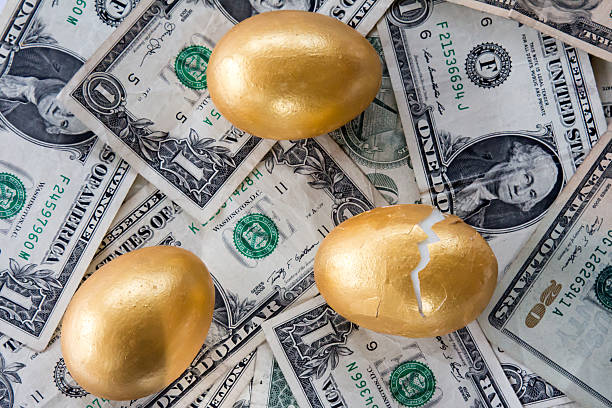 istock Three golden eggs on money and one is cracked 502092330
