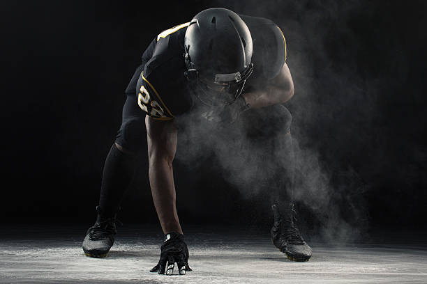 American Football Football player in a three-point stance. football helmet and ball stock pictures, royalty-free photos & images