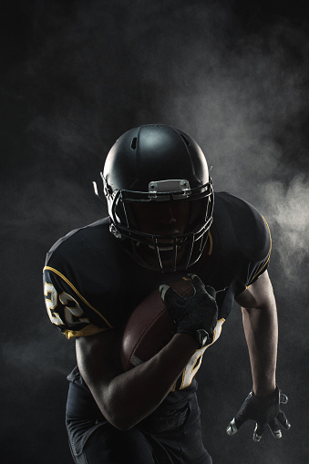 An American Football player and running back in full tackle football pads is ready to play. Image taken in Utah, USA.