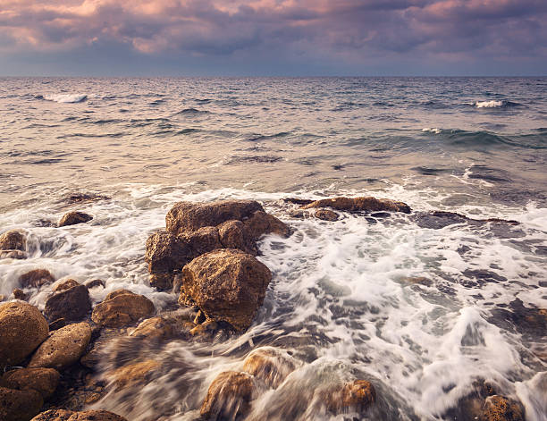 istock Sea waves with rocks on the beach at sunset 502096098