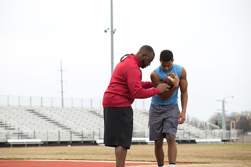Coach giving tips to an athlete on football techniques.