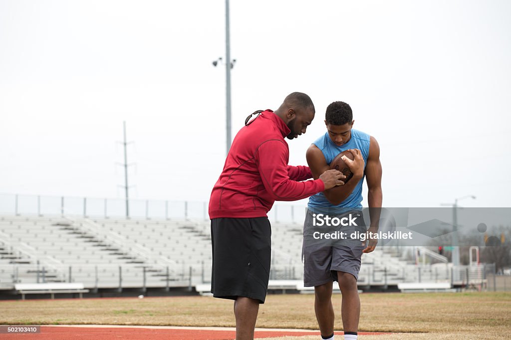 Coach training a high school athlete for football. Coach giving tips to an athlete on football techniques. Coach Stock Photo