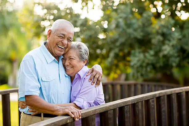 A mexican senior couple laughing together on bridge.