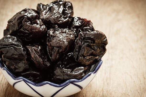 istock dried plums prunes in bowl on wooden table 502118782
