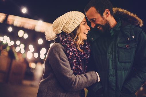 Medium portrait of young Caucasian man and woman in love spending winter day hiking in mountains enjoying view