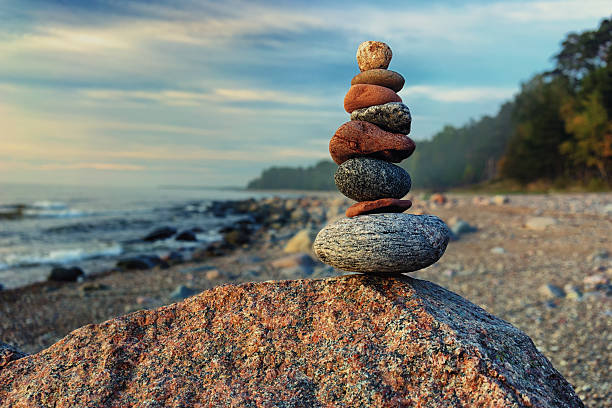 Sustainable cairn at sea in pastel colors Sustainable cairn different shapes on the background of the Baltic Sea and the tranquil forests on the rocky beach in bright pastel colors cairns photos stock pictures, royalty-free photos & images