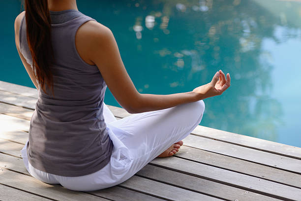 Moment of reflection A relaxed young woman meditating next to a pool outdoorshttp://195.154.178.81/DATA/i_collage/pi/shoots/783592.jpg women exercising swimming pool young women stock pictures, royalty-free photos & images