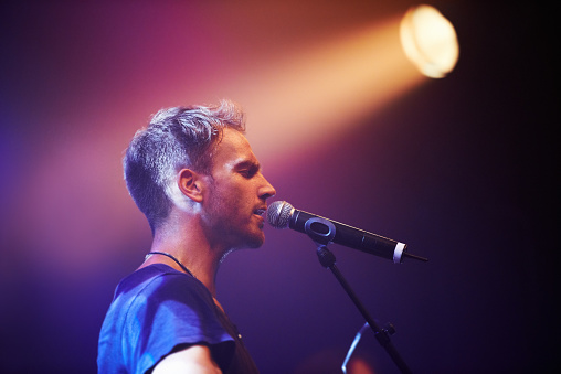 A beautiful shot of a male walking in a wild field and holding a guitar in his hands