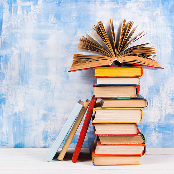 istock Stack of colorful hardback books, open book on blue background 502131066