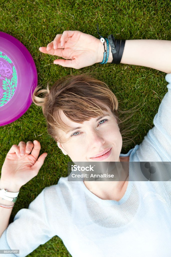 Frisbee player relaxing Close-up portrait of happy young woman resting on the grass after Frisbee game. 20-29 Years Stock Photo