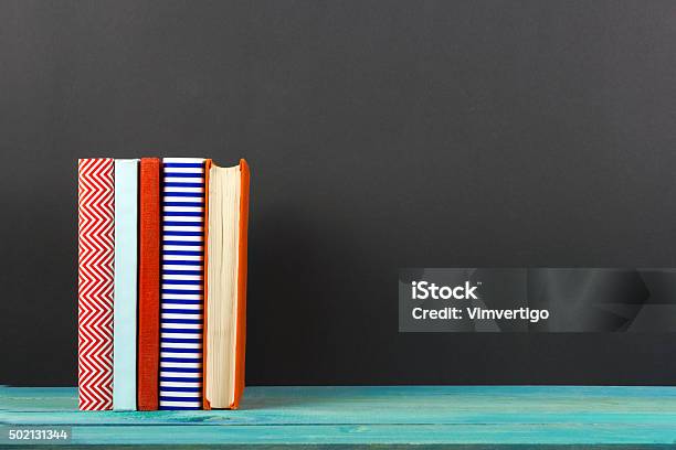 Row Of Colorful Hardback Books Open Book On Black Background Stock Photo - Download Image Now