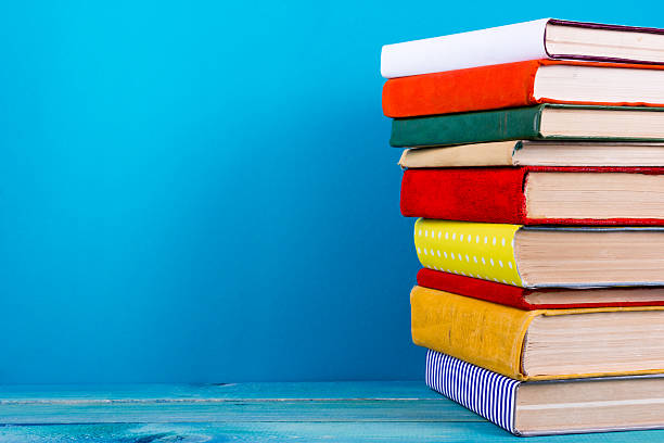 istock Stack of colorful hardback books, open book on blue background 502131388