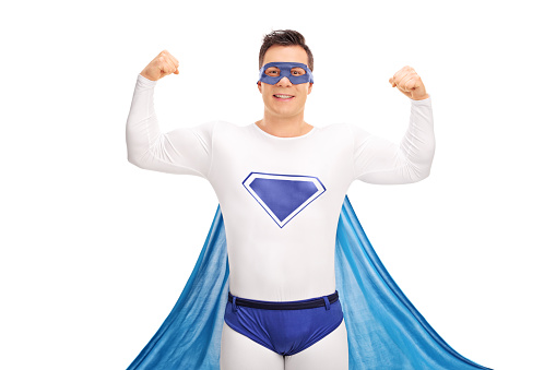 Young male superhero flexing his both hands and looking at the camera isolated on white background