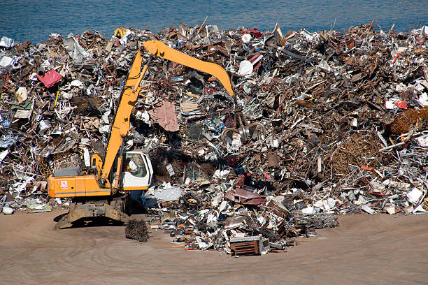 Yellow backhoe working with scrap metal in harbor