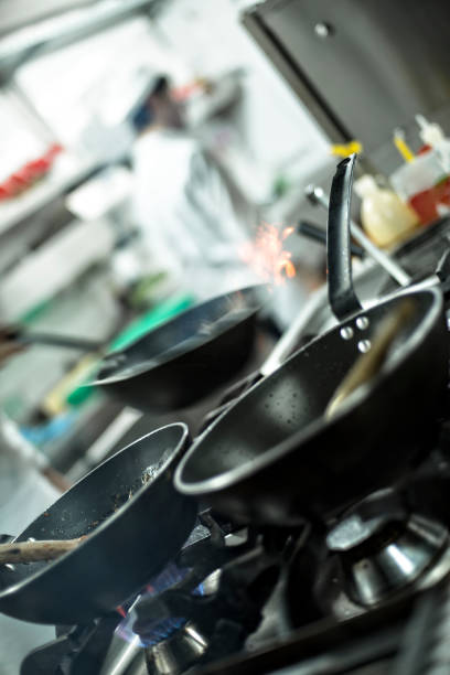 Wok frying with flames in industrial kitchen.