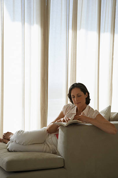 Relaxed Woman Reading Book On Sofa