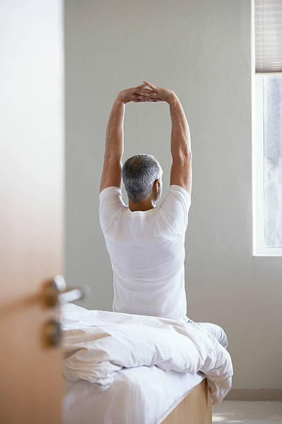 istock Man Stretching Hands While Sitting On Edge Of Bed 502135775